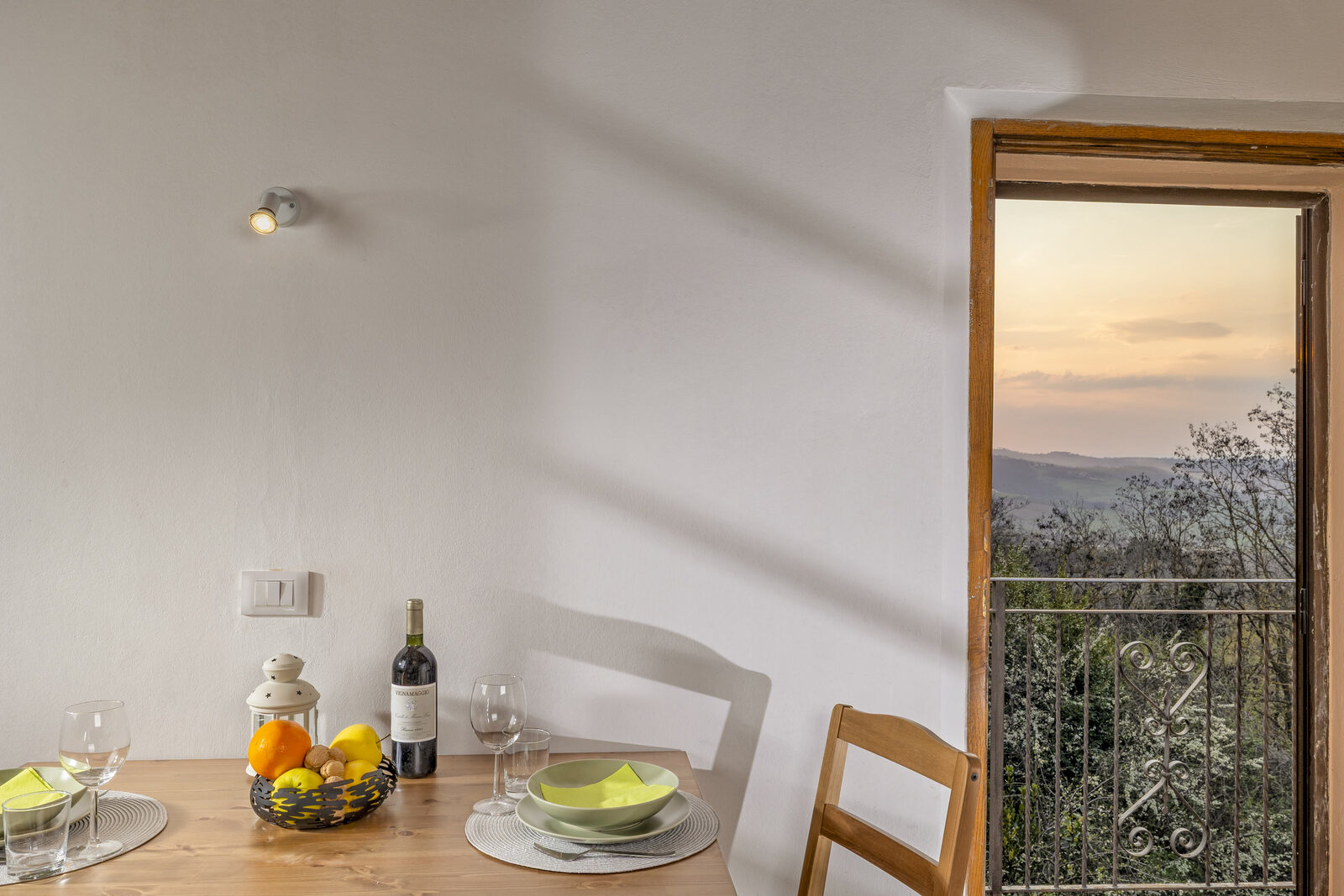Tavola apparecchiata e porta aperta sul tramonto sulle colline, appartamento Il Rifugio