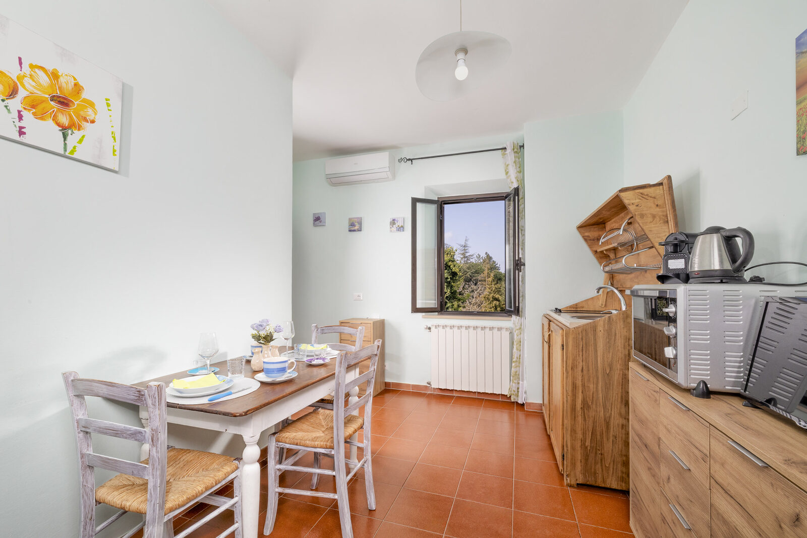 Angolo pranzo con cucina compatta e finestra sul verde, appartamento Il Tino